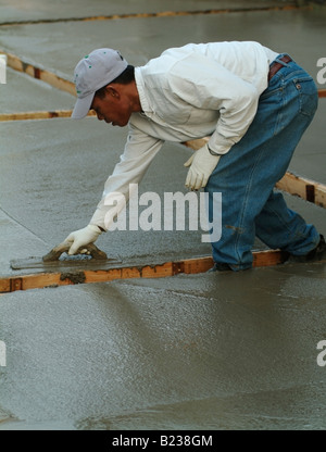 Workman livellamento di calcestruzzo bagnato con un Darby durante la costruzione di un patio nel cortile di una casa privata in California Foto Stock