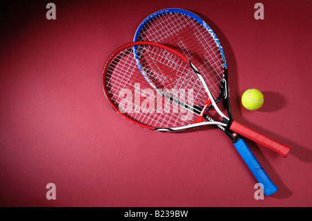 Racchette da tennis e una sfera isolata su sfondo rosso Foto Stock