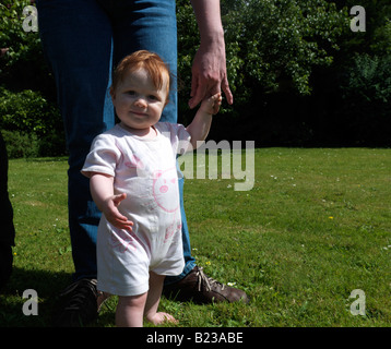 Dieci mesi ragazza bambino ad imparare a camminare Foto Stock