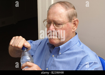 Tentativo di aprire una bottiglia di acqua minerale Foto Stock