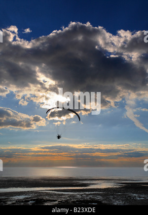 Un powered parapendio vola verso il tramonto sulla spiaggia Heacham sulla costa di Norfolk, Inghilterra, Regno Unito. Foto Stock