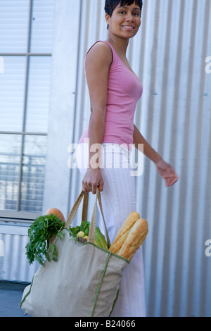 African American donna porta green shopping bag Foto Stock