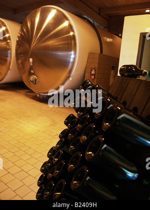 Vasche di fermentazione in backround e bottiglie di vino su riddler di bordo ad un azienda vinicola nella Napa Valley, California Foto Stock