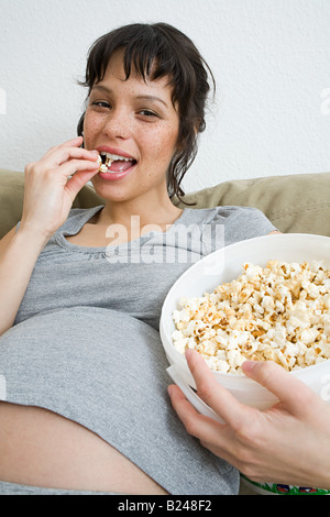 Donna incinta mangiare popcorn Foto Stock