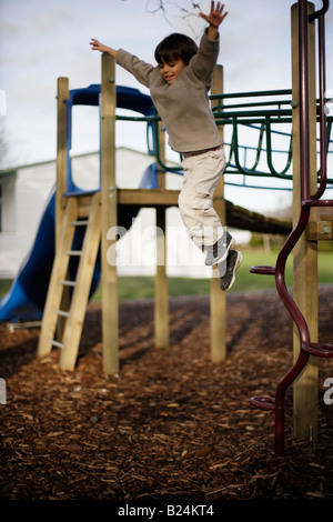 Ragazzo di età compresa tra i sei salti dalla struttura in parco giochi avventura sequenza di immagini Foto Stock