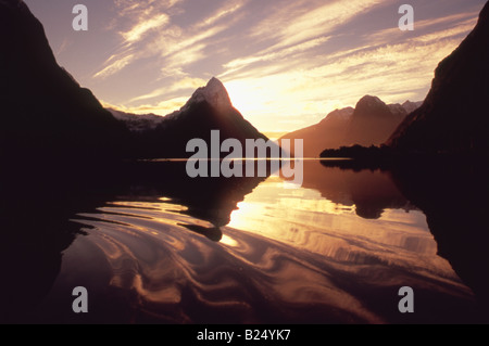 Milford Sound, Fiordland, Nuova Zelanda, al tramonto con il riflesso delle montagne e il cloud computing tra cui la mitica Vetta Mitre, centro. Foto Stock