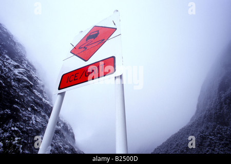 "Attenzione di ghiaccio' roadsignwith sullo sfondo di montagne coperte di neve lungo la scenic Milford Road (autostrada statale 94), Fiordland, NZ Foto Stock