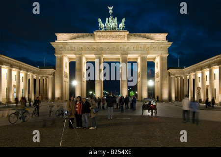 Una vista di turisti scattare fotografie al Brandenburger Tor o Porta di Brandeburgo al tramonto di sera. Foto Stock