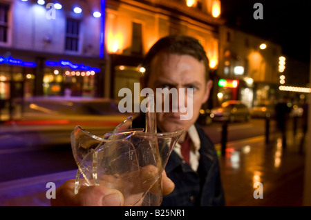 L'uomo minaccioso con la rottura di una bottiglia di vetro Foto Stock