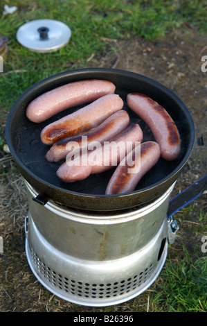 Salsicce cottura su un fornello da campeggio Foto Stock