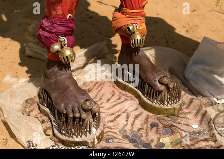 Un sadhu sorge sotto un ombrello mentre in piedi sulle scarpe di chiodi a Talakkad in Karnataka. Foto Stock