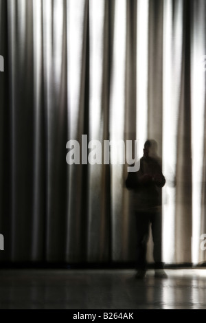 Persona e scuro lungo le tende oscuranti in camera Foto Stock