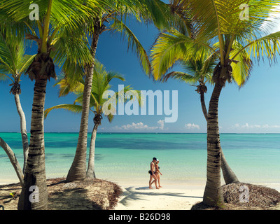 Repubblica Dominicana, Punta Cana, Bavaro Beach, palme sulla spiaggia di sabbia bianca di fronte al mare con la giovane a piedi da Foto Stock