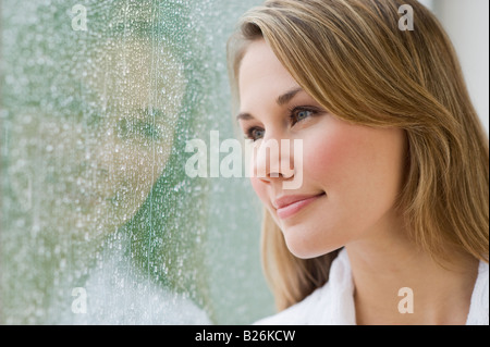 Donna che guarda fuori la finestra delle piogge Foto Stock
