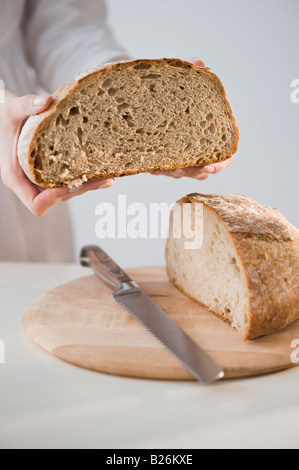 Donna che mantiene pagnotta di pane Foto Stock