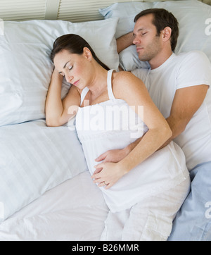 Gravidanza coppia ispanica dormire nel letto Foto Stock