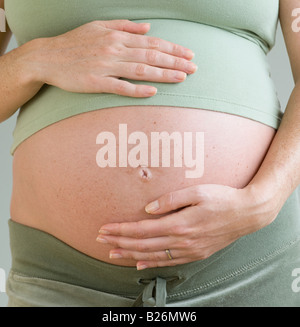 Donna incinta con le mani sulla pancia Foto Stock