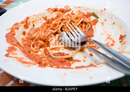 Avanzi di pasta sulla piastra con cucchiaio e forchetta Foto Stock