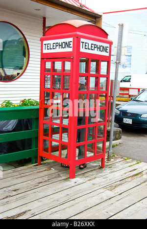 Persona nel vecchio rosso pay cabina telefonica nella baia di vacca, Prince Rupert BC Foto Stock