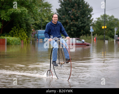 TEWKESBURY RESIDENT GRAHAM WEATHERLY cavalca il suo Penny Farthing attraverso l'acqua durante le inondazioni nel Gloucestershire Luglio 2007 U Foto Stock