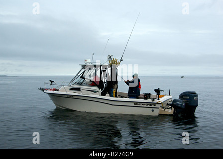Il pescatore a bordo di un fuori bordo powered pesce sport cruiser giocando un salmone agganciato troll pesca con downriggers Foto Stock