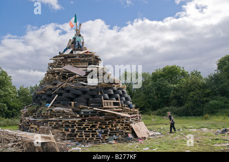 L'uomo la preparazione di xi luglio falò con un'effigie in cima, Monkstown, Irlanda del Nord Foto Stock