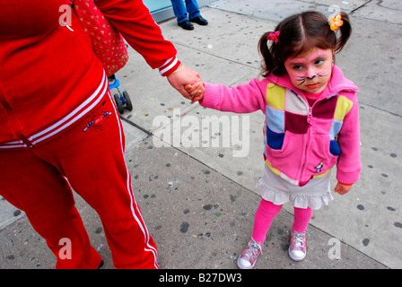 Una ragazza ispanica con il suo volto dipinto come un gatto tenendo la sua mamma la mano Foto Stock