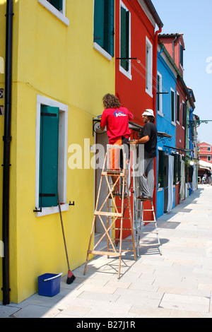 Operai che fissa una finestra su una casa dipinta a Burano ,Laguna veneziana,Italia Foto Stock