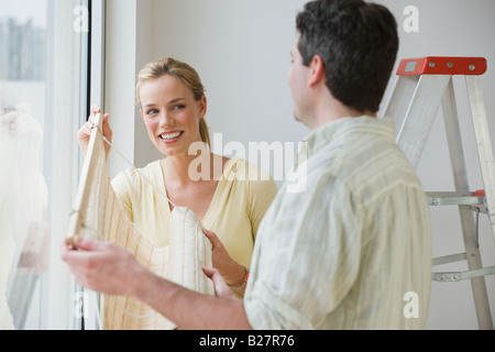 Giovane appendere i ciechi della finestra Foto Stock