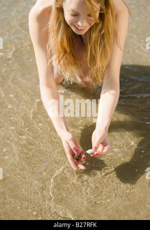 Donna di prelevare conchiglie in spiaggia Foto Stock