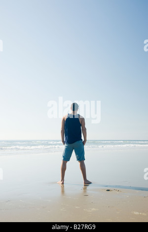 Uomo in piedi sulla spiaggia Foto Stock