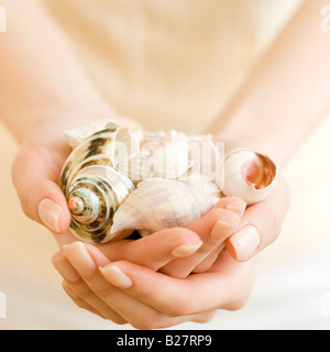 Donna che mantiene manciata di conchiglie Foto Stock