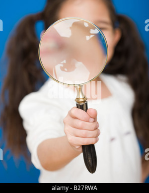 Ragazza ispanica tenendo la lente di ingrandimento Foto Stock