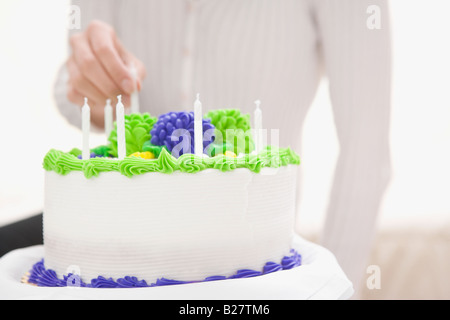 Donna mettendo la candela sulla torta di compleanno Foto Stock