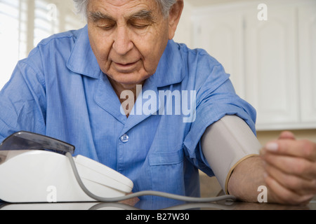 Senior uomo prendendo proprio la pressione sanguigna Foto Stock