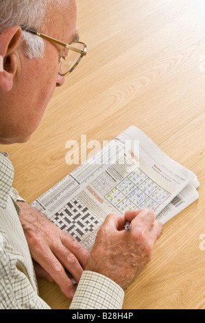 Un uomo anziano concentrando su un puzzle Sudoku in un giornale. Foto Stock