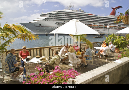 I passeggeri delle crociere in Roseau relax al dockside cafe vicino a loro Carnival Cruise Lines nave destino Foto Stock