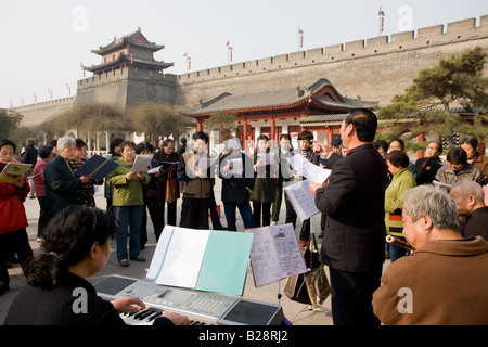 Le persone si radunano per formare un coro informale parte dell'esercizio mattutino nel parco dalla parete della città Xian Cina Foto Stock