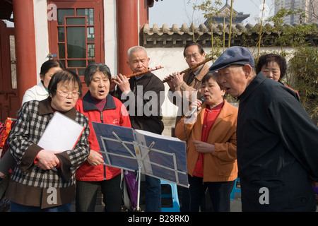 Le persone si radunano per formare un coro informale parte dell'esercizio mattutino nel parco dalla parete della città Xian Cina Foto Stock