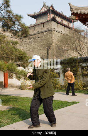 Le pratiche di uomo Tai chi come parte del suo esercizio mattutino nel parco dalla parete della città di Xian Cina Foto Stock