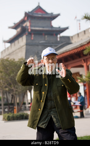 Le pratiche di uomo Tai chi come parte del suo esercizio mattutino nel parco dalla parete della città di Xian Cina Foto Stock