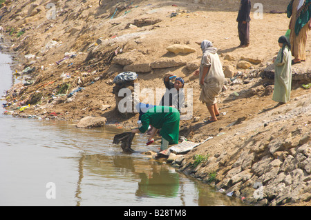 Le donne del villaggio lavare i loro vestiti e piatti in un canale di irrigazione nei pressi di El Fayoum Egitto Foto Stock