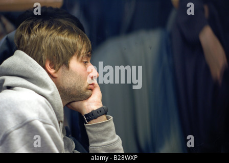 Giovane uomo cerca attraverso il finestrino del treno, annoiato Foto Stock