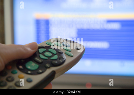 Sky TV + telecomando puntato verso lo schermo del televisore che mostra il cielo di pagina degli elenchi. Regno Unito Foto Stock