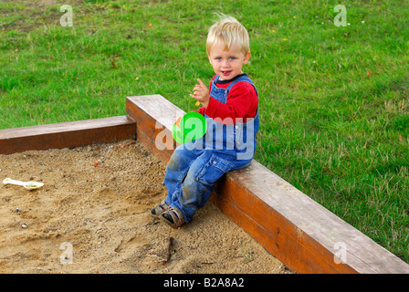 Baby boy bionda nella buca di sabbia la riproduzione di giocattoli giochi per bambini 2 - 3 anni Foto Stock