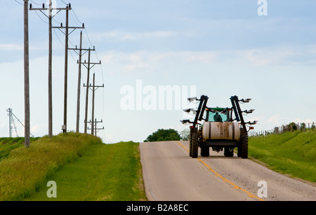 Un agricoltore guidando il trattore su strada dopo la concimazione i suoi campi. Foto Stock