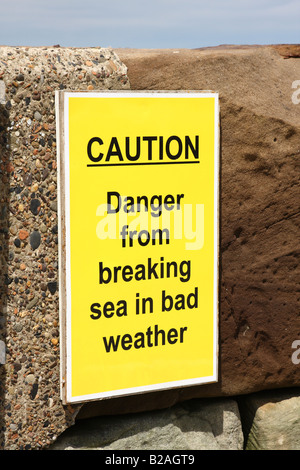 Avvertenza di sicurezza segno su una parete del porto a Whitby, North Yorkshire, Inghilterra, Regno Unito Foto Stock