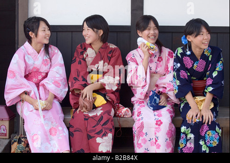 Le quattro ragazze vestito in cotone colorato di accappatoi Yukata prendendo una pausa nella calda estate il calore in un piccolo locale festival della città Foto Stock