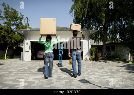 Coppia giovane sul vialetto con scatole bilanciata sui capi Foto Stock