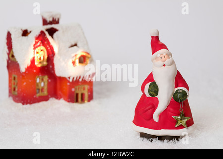 Casa Natale e Babbo Natale fatti di argilla sulla neve artificiale Foto Stock